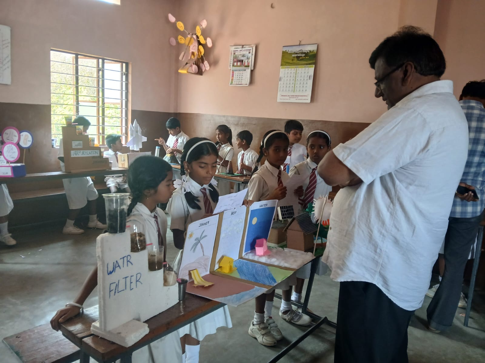 Students present their water filter and weather-themed projects to an evaluator.