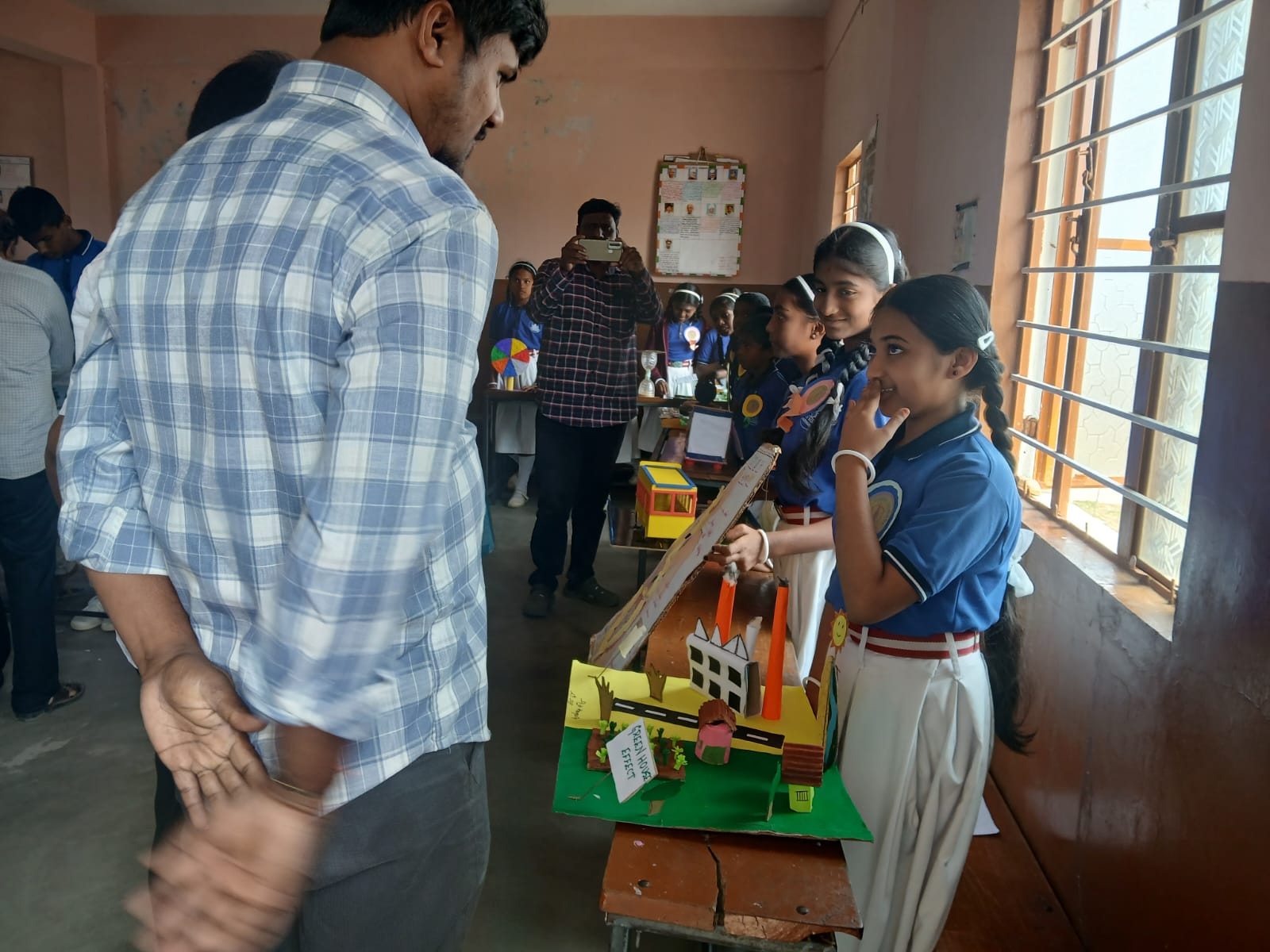 Students confidently explain their working model to a teacher during the science fair.