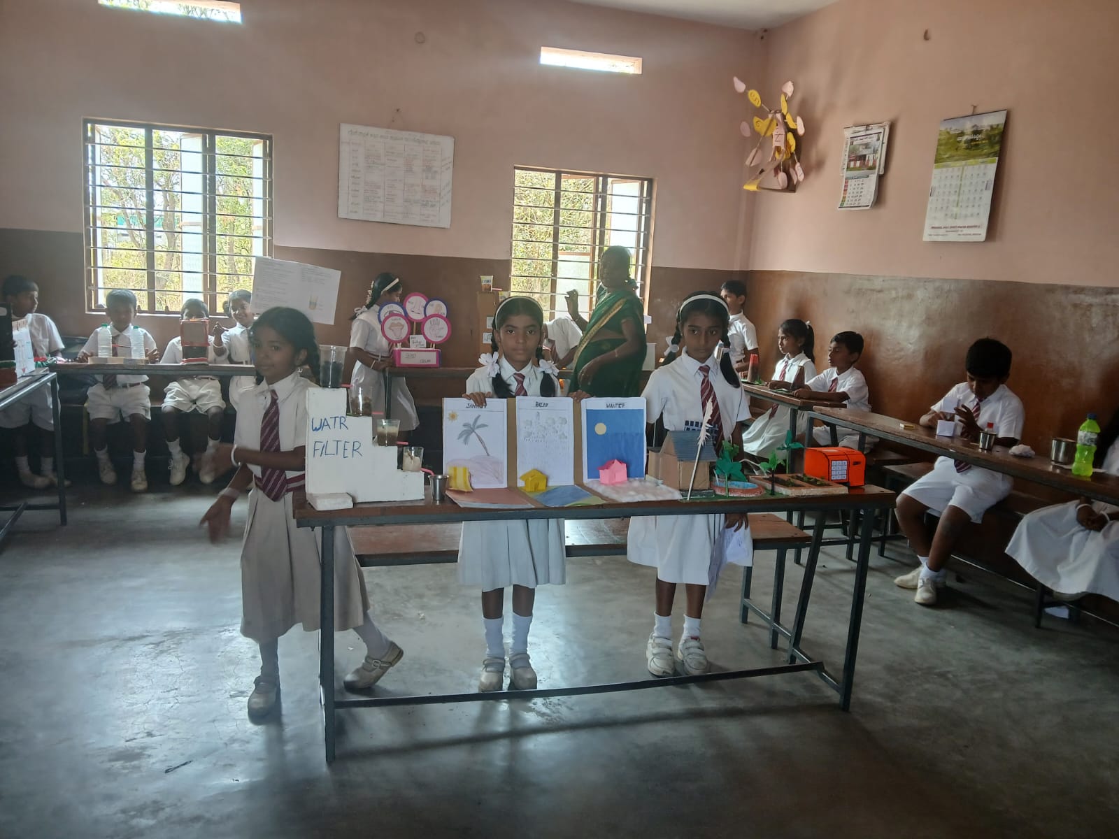 Young students proudly present their creative science models during a classroom exhibition.